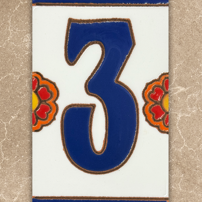 Decorative tile with the number '3' in blue, surrounded by floral designs on a beige background