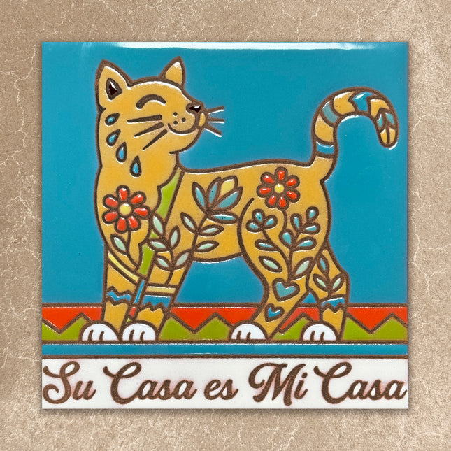 Decorative tile with a cat design and 'Su Casa es Mi Casa' text on a textured beige background