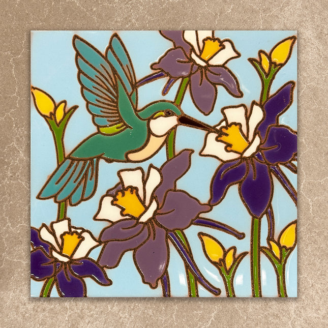 Decorative tile with a hummingbird and flowers on a blue background