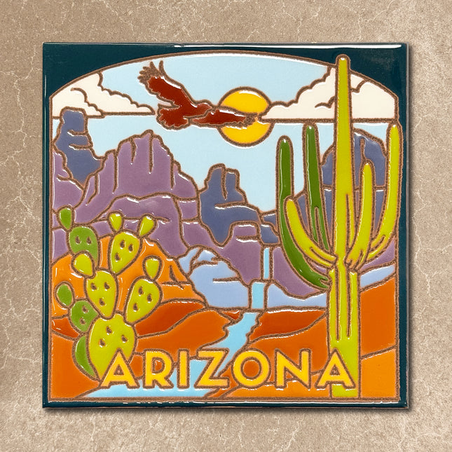 Ceramic tile with desert landscape design featuring cacti and an hawk, with 'Arizona' text.