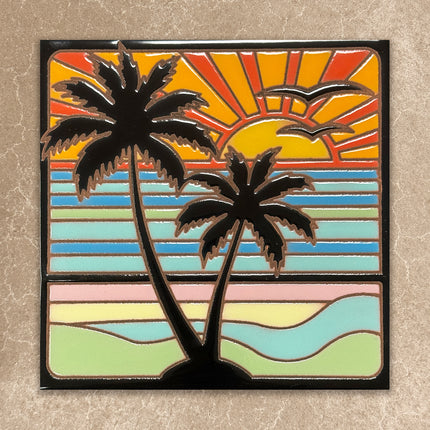 ceramic tile art of palm trees with a colorful sunset background on a textured wall.