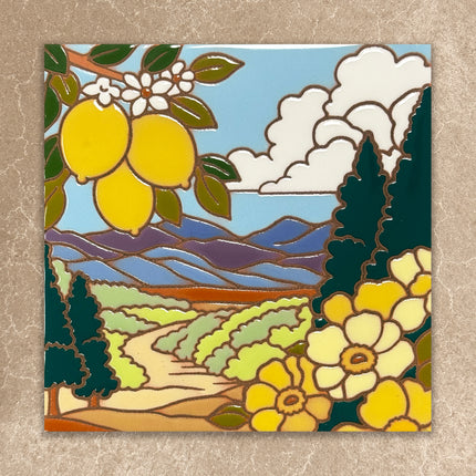 Decorative tile with a landscape design featuring lemons, flowers, and mountains on a beige background.