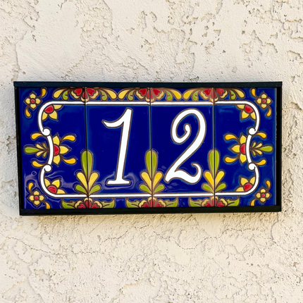 Decorative house number '12' on a textured wall with floral designs