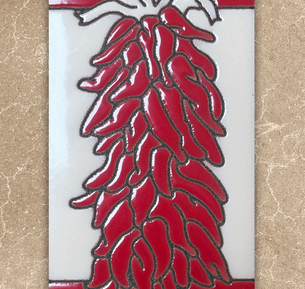 Decorative tile with red chili design on a beige background