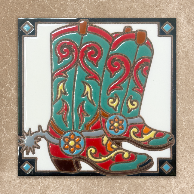 A square decorative tile or plaque featuring an illustrated pair of cowboy boots with turquoise, red, yellow, and brown details, set against a white center and a textured beige background.