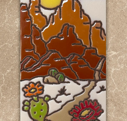 Decorative tile with desert landscape design featuring mountains, sun, cacti, and birds on a beige background.