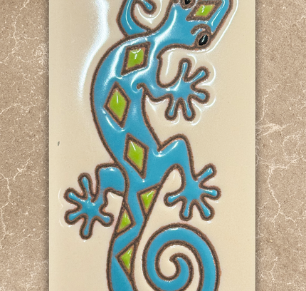 Decorative tile with a blue and green lizard design on a beige background