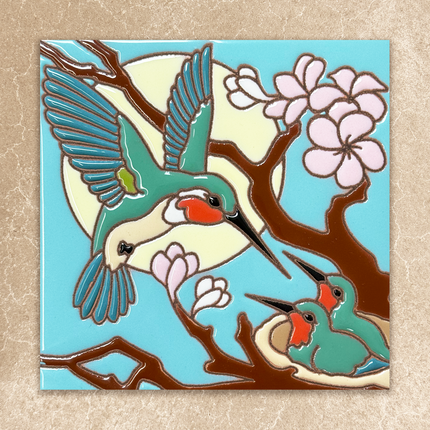 Decorative tile with a stylized illustration of a hummingbird and cherry blossoms on a blue background.